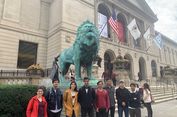 a group of students posing in front of Chicago art institute entrance with flags and a lion statue
