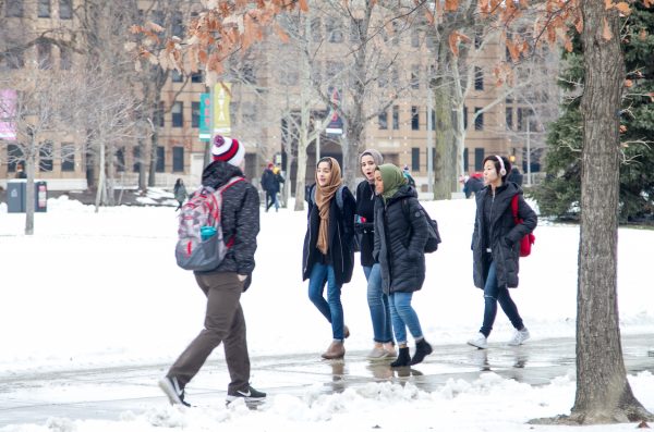 students in winter coats walking on campus covered in snow