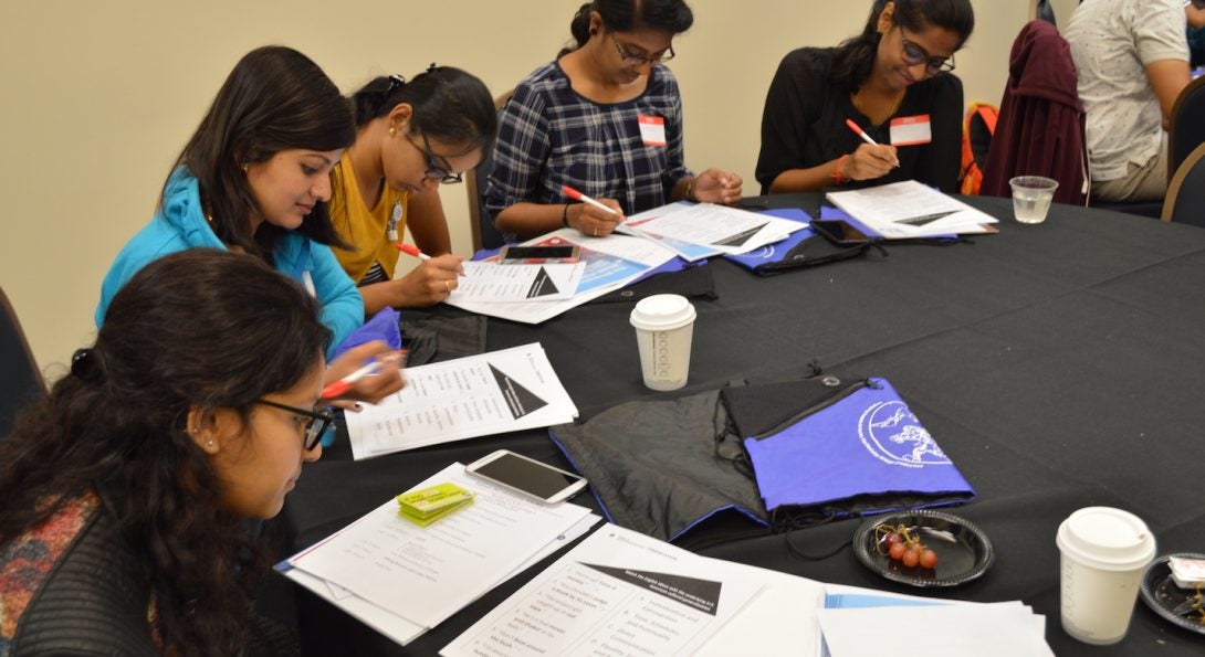 Five students at a round table review a workshop handout.