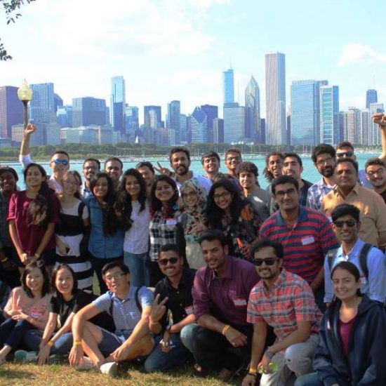 A large group of international students pose together, smiling, in front of the Chicago skyline.