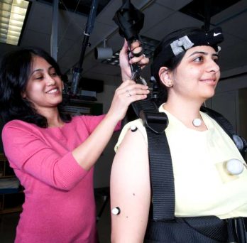 A student adjusts a medical device bracing a person's head and shoulders. 