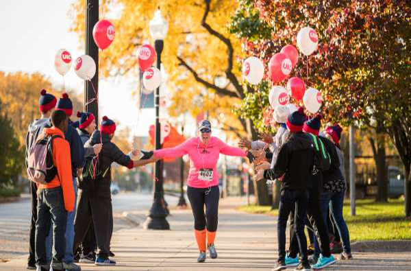 people cheering a runner with pink and white UIC balloons