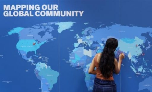 Student stands with back to camera while placing a flag pin on their home country during the Mapping Our Global Community welcome activity.