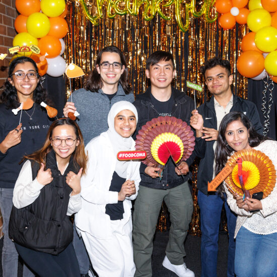 UIC international students pose in front of a yellow and orange backdrop that says 