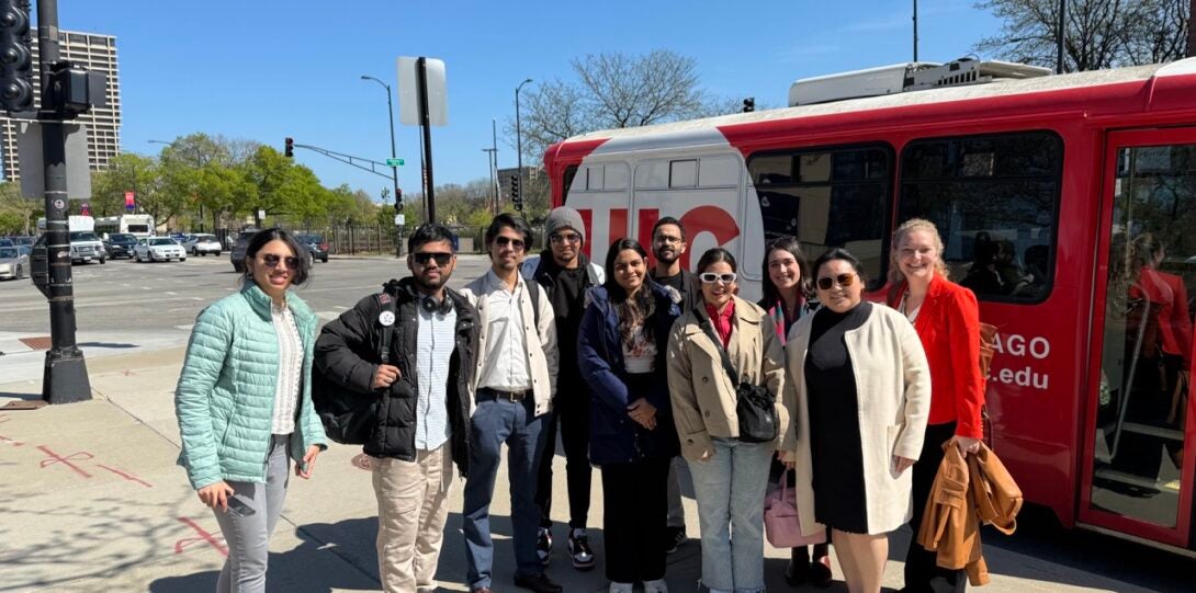 A group of student stand outside a minibus with the UIC logo on it.