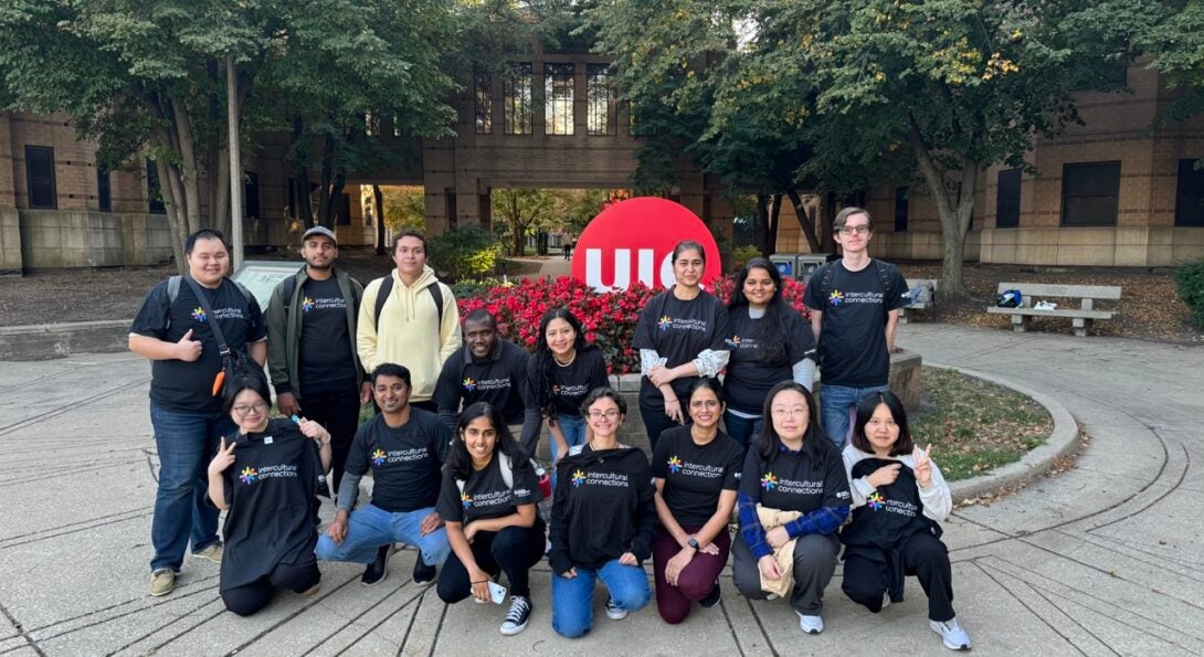 Group of students wearing the Intercultural Connections t-shirt pose on the stairs of the SSB lobby.