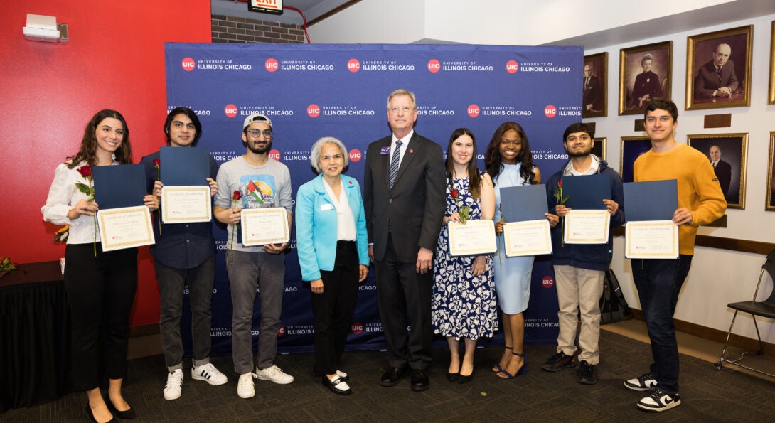 seven students pose with certificates in hand. UIC Chancellor and Vice Provost for Global Engagement stand in the center.